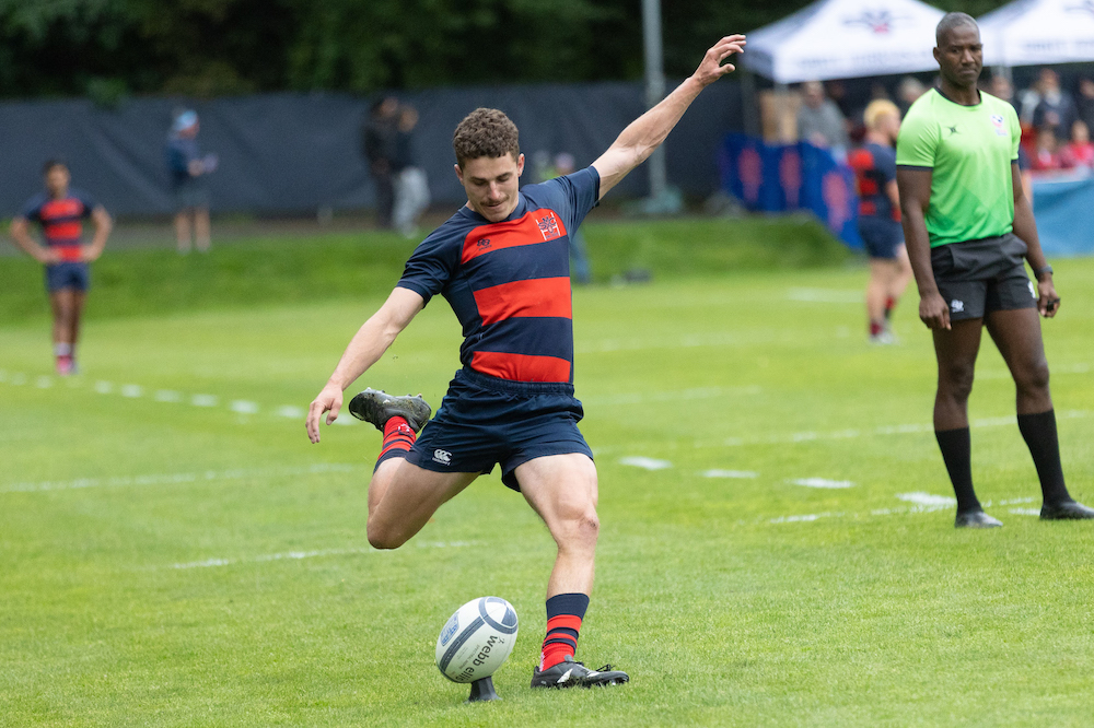 Men's Rugby Player Erich Story kicks against Cal while a referee watches, April 2024