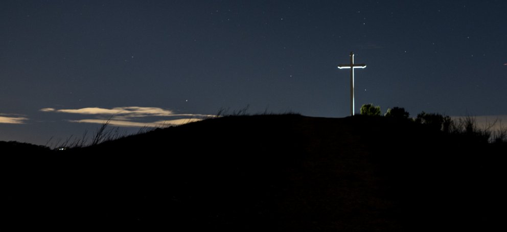 Cross on a hill, night sky in the background