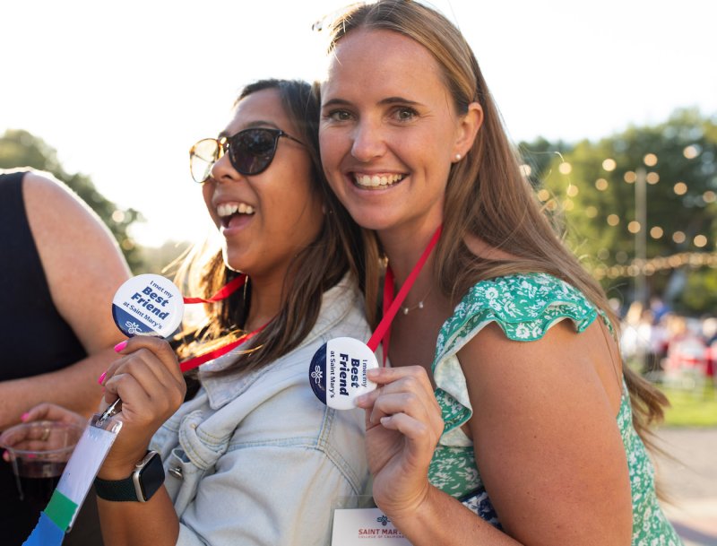 Kristina Reyes '14 and Megan Dorsey '14 smile with buttons reading: I met my best friend at Saint Mary's