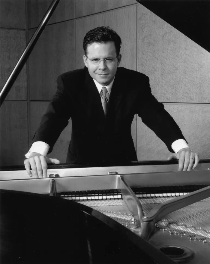 A Black-and-White photo of Dr. Scott Holden at the piano, starting at camera