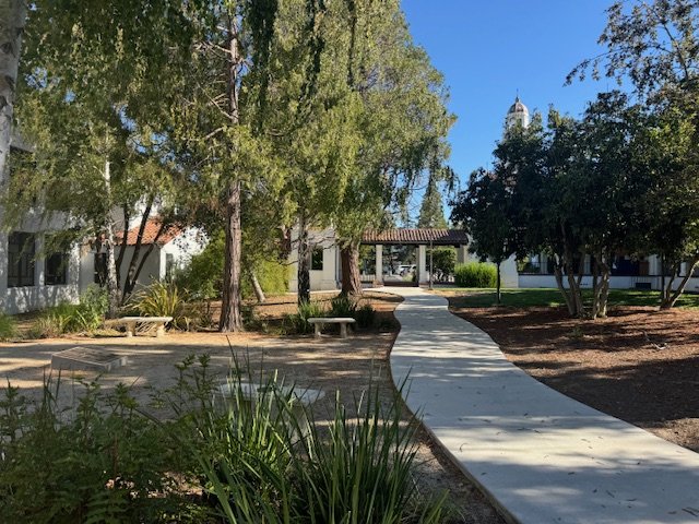 A picture of the Veterans Garden, sidewalk and benches with the SMC bell tower in the background