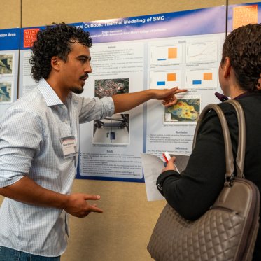 Student pointing at their conference poster