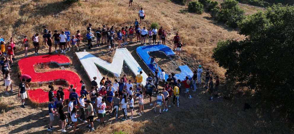Students standing next to the letters S, M and C