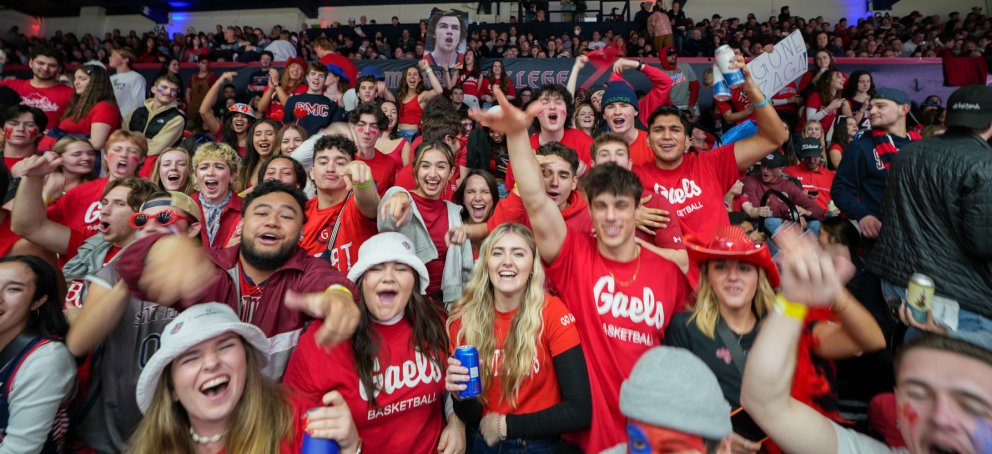 Students cheering wearing Gaels shirts at a basketball game