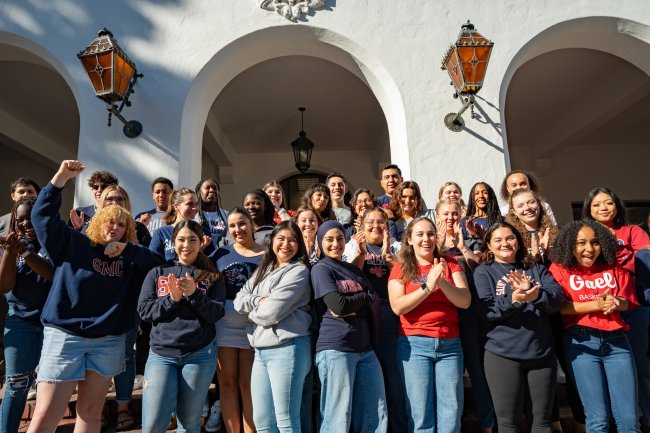 Group of Resident Advisors standing outside on the steps at Saint Mary's  clapping, cheering, and smiling.