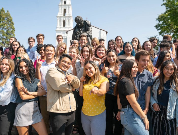 Students in a group smiling in front of the saint mary's college campus