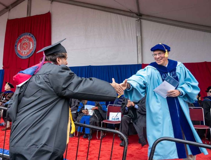 A saint mary's college graduate shaking hands with a faculty member